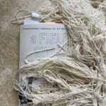 Image by Carolyn Hall: The Field guide on an off-white carpet under off-white tassels